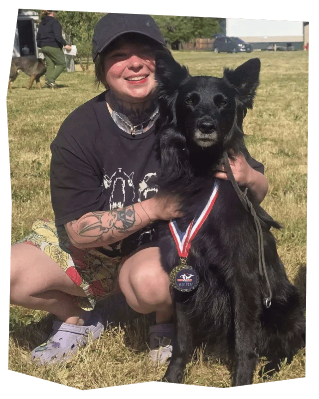 Frank kneeling next to Kismet, who is wearing two medals after winning the Ruttengshunde RH-FL FL V trial.